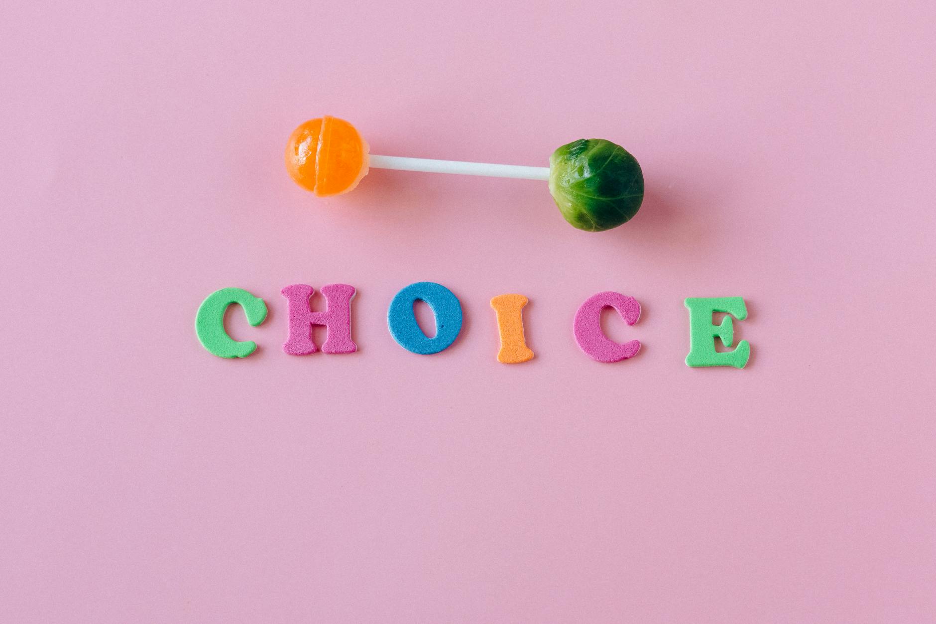 Colorful choice between candy and vegetable on pink background.