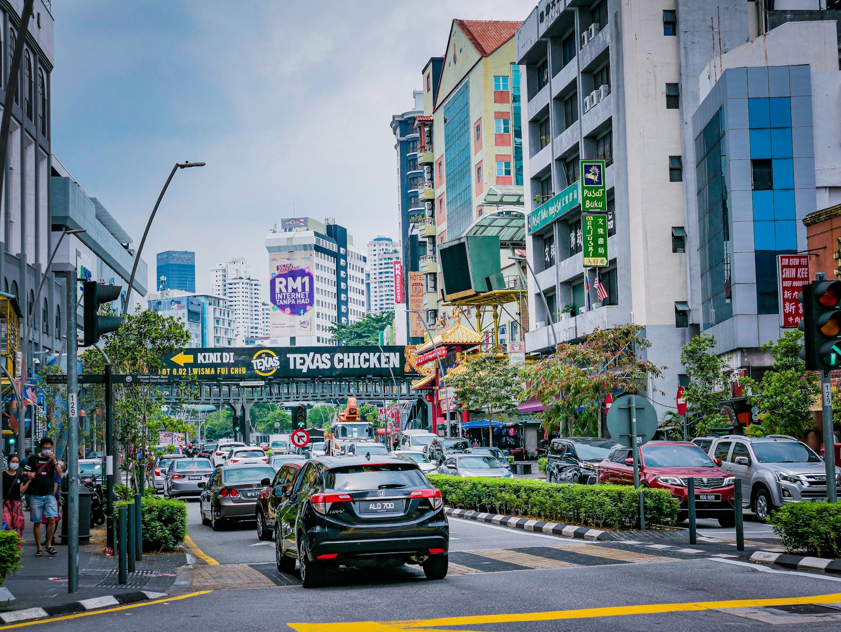 Vibrant city street scene in Kuala Lumpur featuring traffic and diverse architecture.
