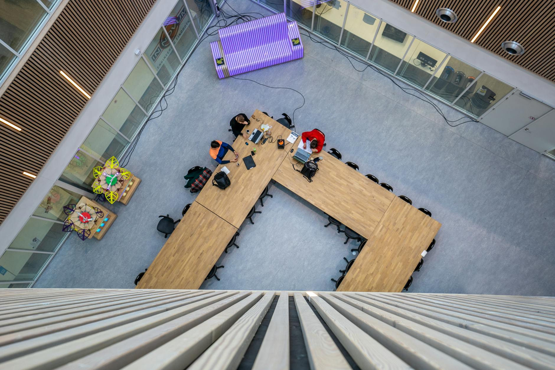 Aerial view of a modern conference room with tables and people working.