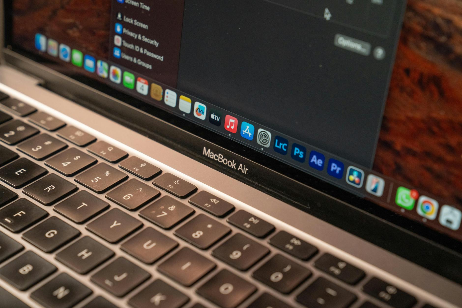 A detailed view of a MacBook Air with a focus on the keyboard and screen displaying app icons.
