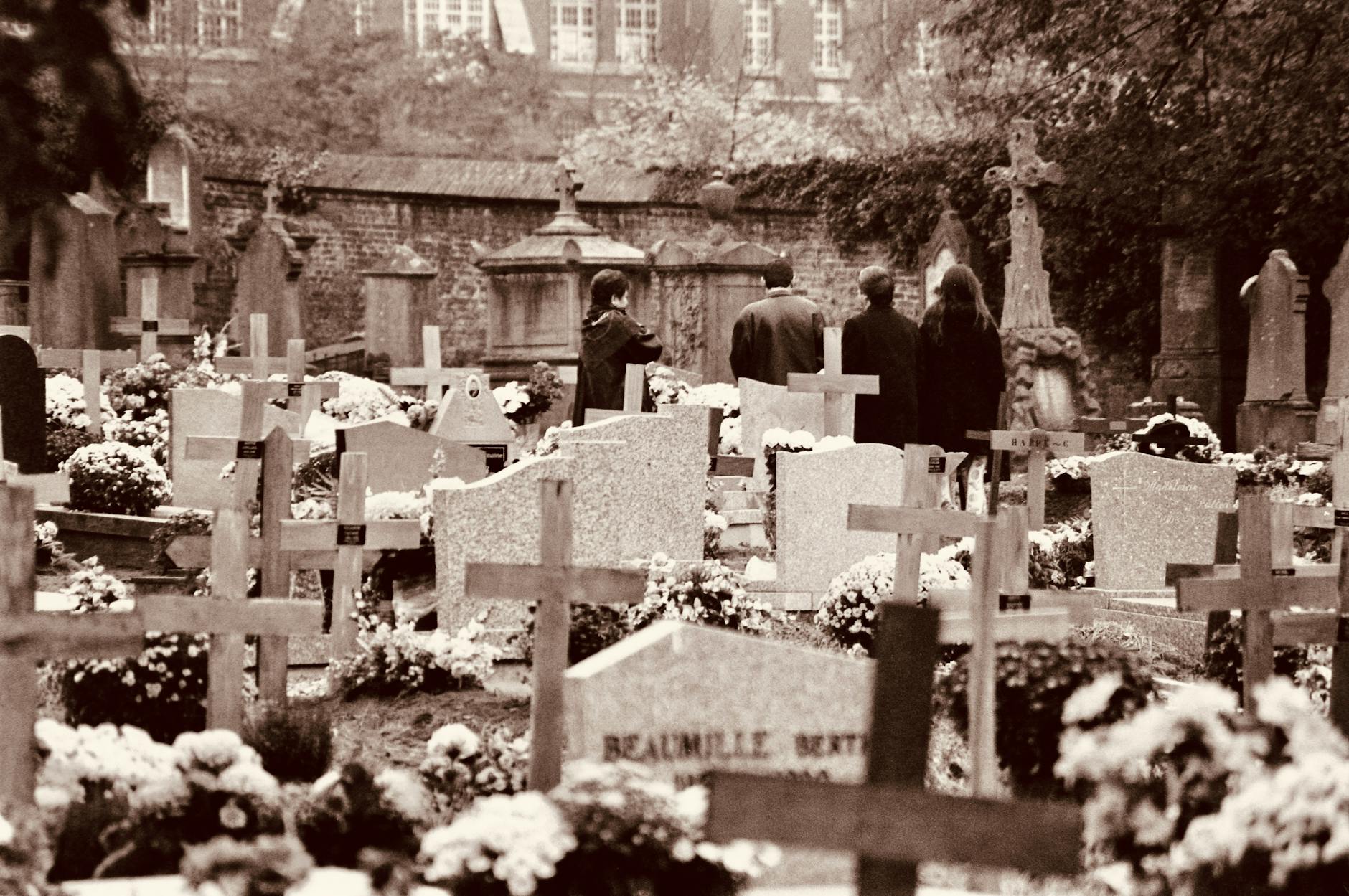 A somber scene of people grieving in a historic cemetery with tombstones.