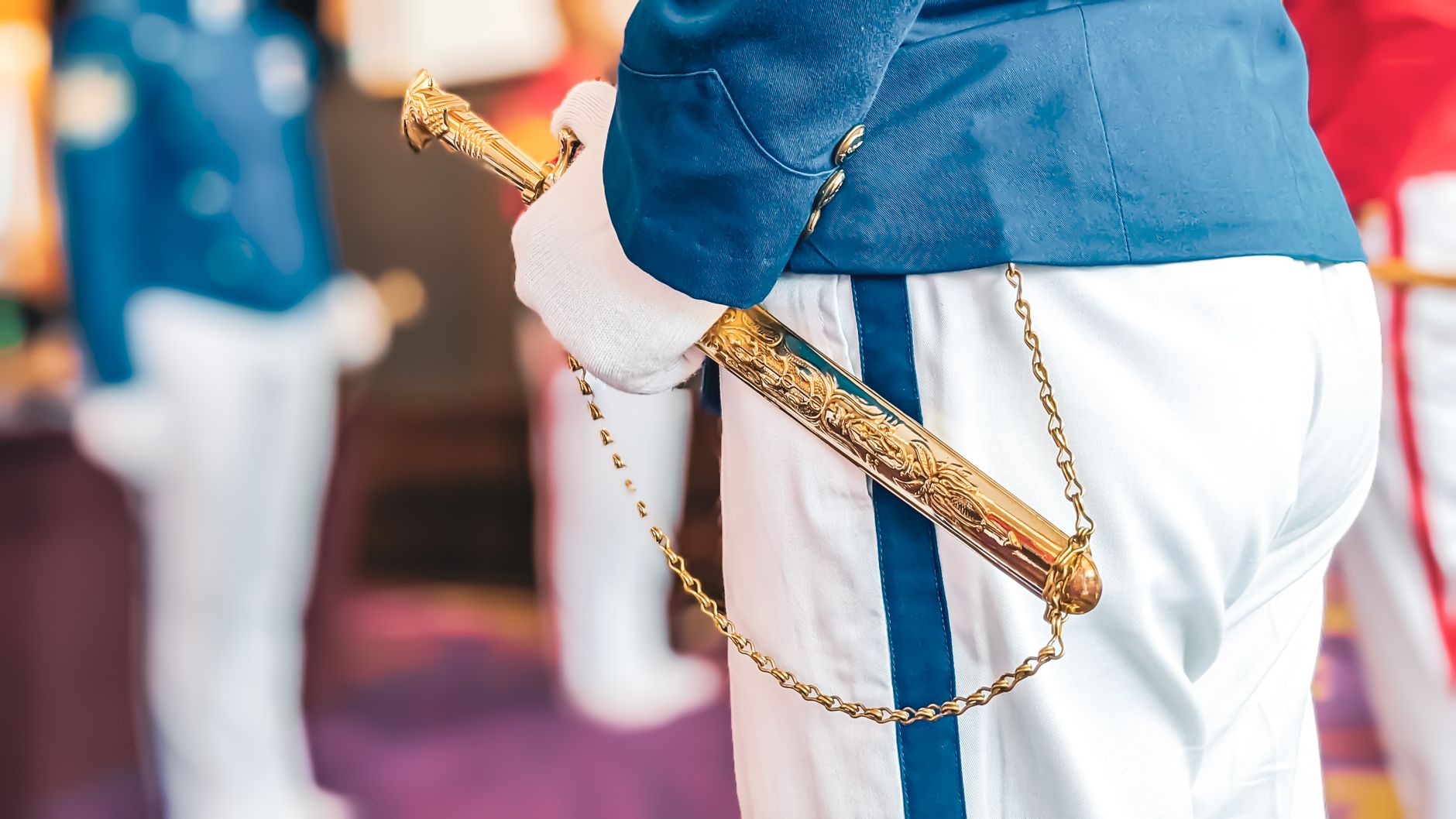 Close-up of a military officer in uniform holding an ornate ceremonial sword indoors.