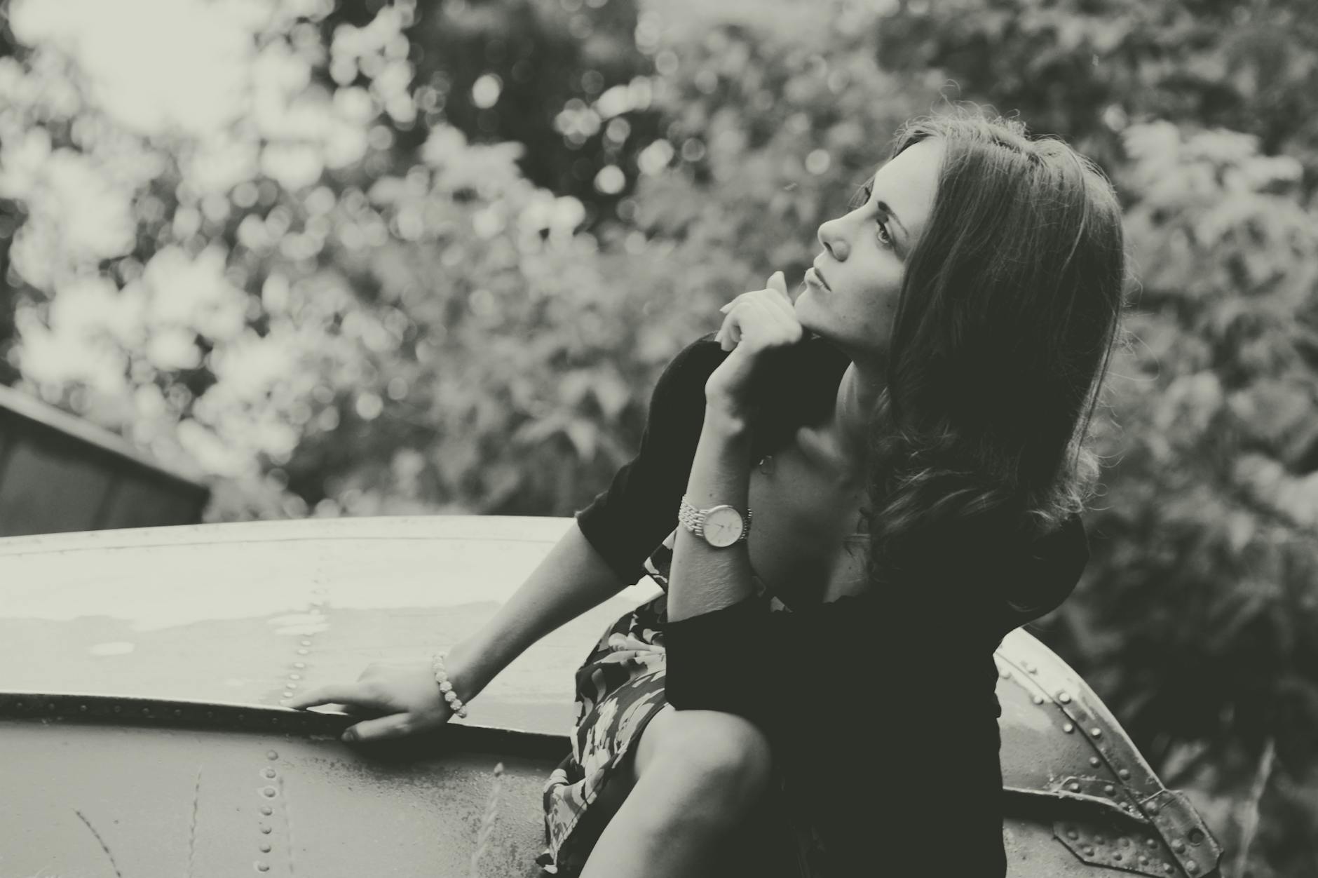 Monochrome photo of a thoughtful woman outdoors, exuding elegance and fashion.