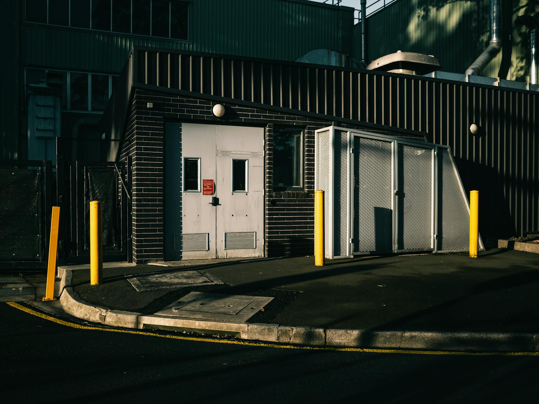Exterior view of an industrial building with metal doors and bollards.