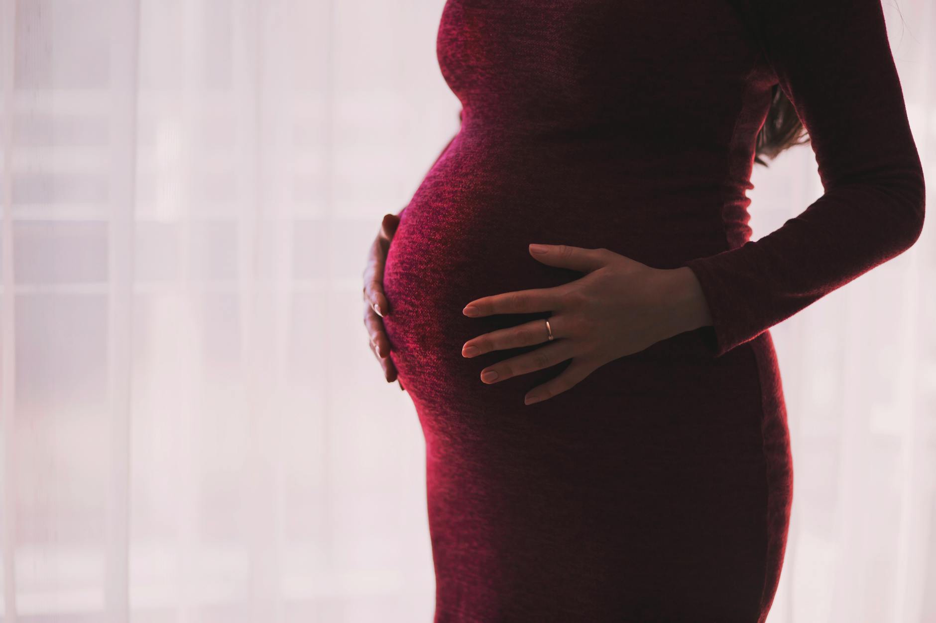 Silhouette of a pregnant woman gently holding her belly, emphasizing motherhood and anticipation.