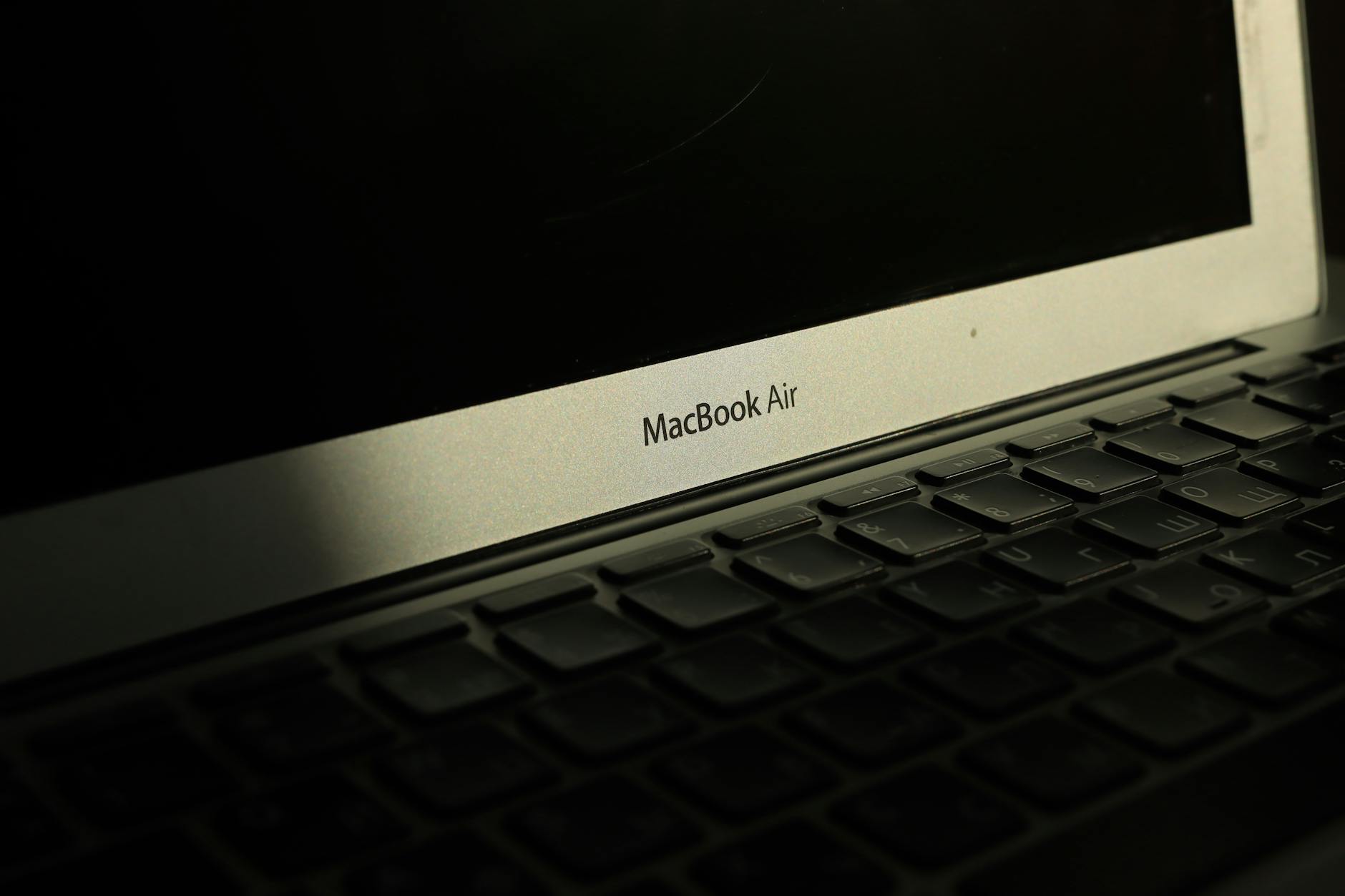 Close-up of a sunlit MacBook Air laptop showcasing its keyboard and screen with shadow effects.